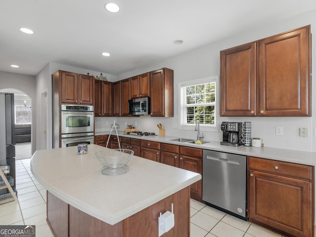 1613 Brolington Ct, Conyers, GA 30013 - kitchen with appliances with stainless steel finishes, arched walkways, light tile patterned floors, light countertops, and a kitchen island