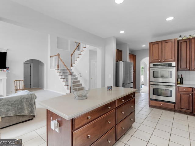 1613 Brolington Ct, Conyers, GA 30013 - kitchen with stainless steel appliances, arched walkways, light tile patterned floors, open floor plan, and light countertops