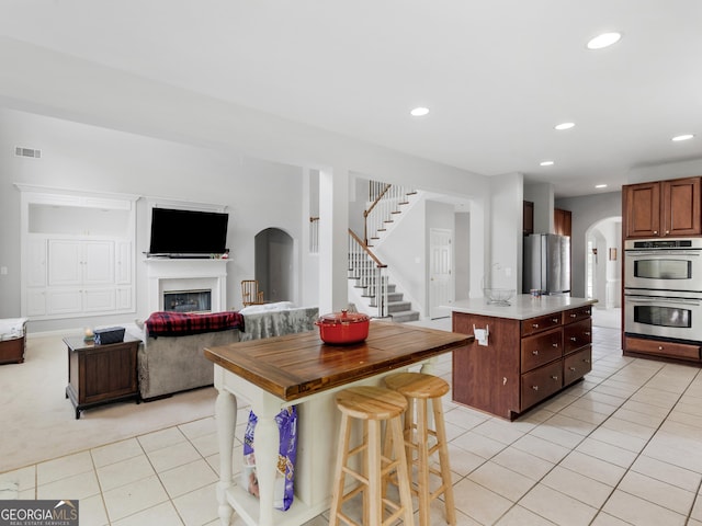 1613 Brolington Ct, Conyers, GA 30013 - kitchen featuring stainless steel appliances, light tile patterned floors, arched walkways, open floor plan, and recessed lighting