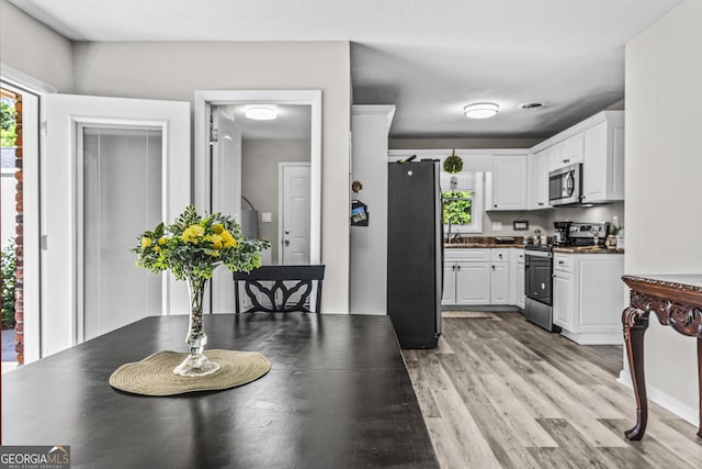 3182 Willow Creek Rd, Augusta, GA 30909 - kitchen featuring appliances with stainless steel finishes, dark countertops, white cabinets, and light wood-style floors