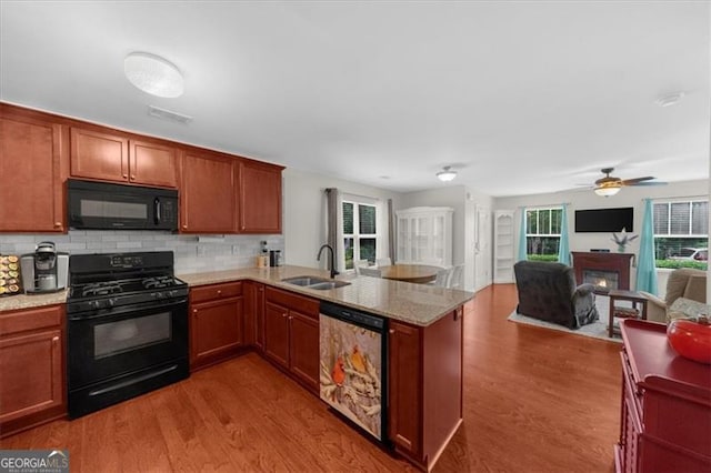 397 Cypher Dr, Suwanee, GA 30024 - kitchen featuring black appliances, a peninsula, wood finished floors, open floor plan, and tasteful backsplash