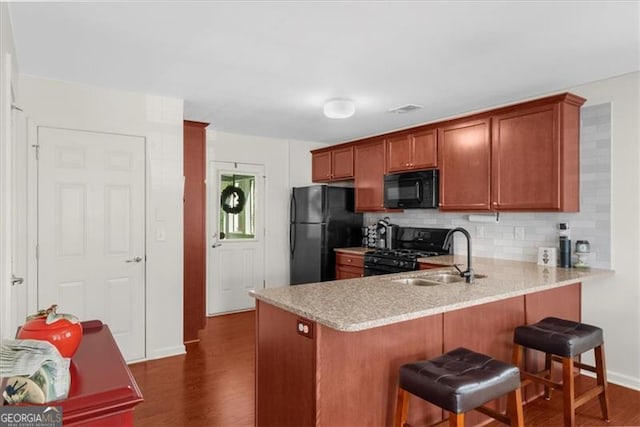 397 Cypher Dr, Suwanee, GA 30024 - kitchen featuring black appliances, light countertops, dark wood finished floors, a peninsula, and backsplash