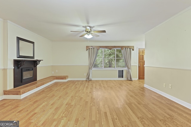 2317 Ga Highway 24, Statesboro, GA 30461 - unfurnished living room featuring ceiling fan, light wood-type flooring, ornamental molding, and a glass covered fireplace
