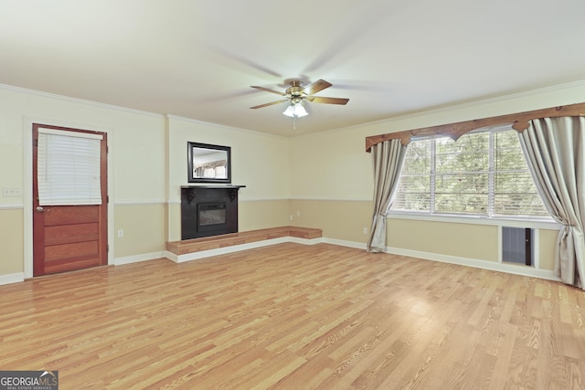 2317 Ga Highway 24, Statesboro, GA 30461 - unfurnished living room with light wood-type flooring, a glass covered fireplace, a ceiling fan, and crown molding