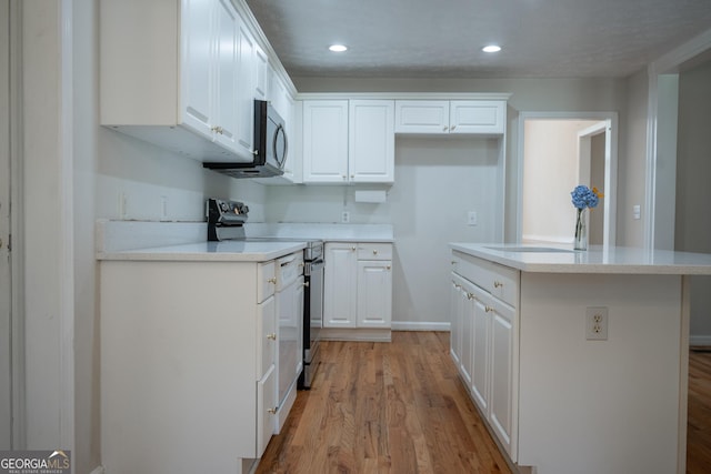 2021 Windfield Dr, Monroe, GA 30655 - kitchen with electric stove, white cabinetry, light wood-style flooring, a kitchen island, and recessed lighting