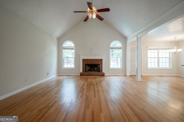 2021 Windfield Dr, Monroe, GA 30655 - unfurnished living room featuring a ceiling fan, a brick fireplace, light wood finished floors, a chandelier, and high vaulted ceiling