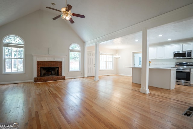 2021 Windfield Dr, Monroe, GA 30655 - unfurnished living room with ceiling fan, light wood finished floors, high vaulted ceiling, a chandelier, and a fireplace