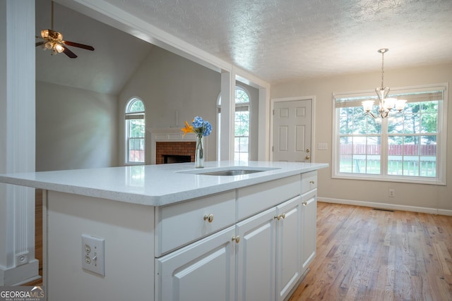 2021 Windfield Dr, Monroe, GA 30655 - kitchen featuring a fireplace, white cabinets, a chandelier, ceiling fan, and light stone countertops