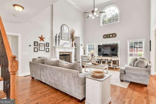 125 Shamus Way, Jefferson, GA 30549 - living area with ceiling fan, a towering ceiling, a fireplace, light wood-type flooring, and ornamental molding