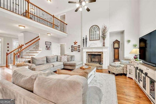 125 Shamus Way, Jefferson, GA 30549 - living area featuring a towering ceiling, ceiling fan, stairway, light wood finished floors, and a fireplace with raised hearth