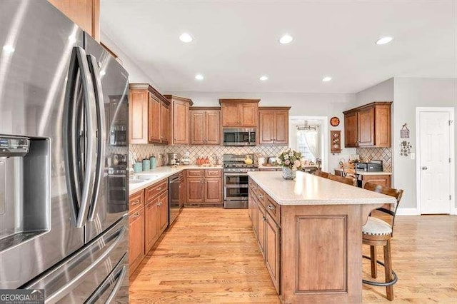125 Shamus Way, Jefferson, GA 30549 - kitchen featuring stainless steel appliances, a breakfast bar, a kitchen island, light wood-style floors, and decorative backsplash