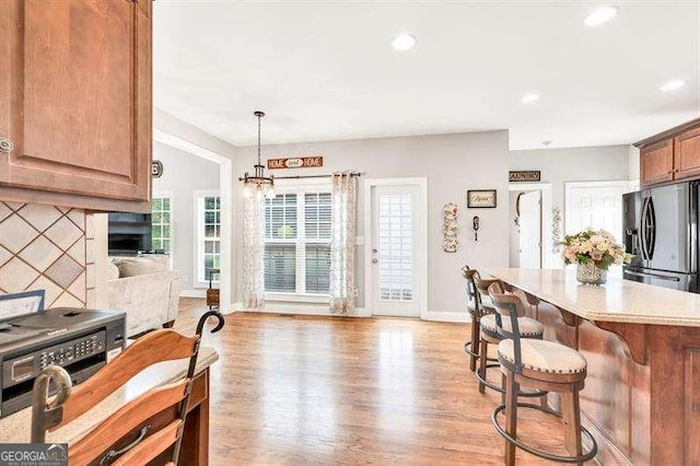 125 Shamus Way, Jefferson, GA 30549 - kitchen featuring stainless steel fridge with ice dispenser, a kitchen bar, light wood-style flooring, light countertops, and recessed lighting