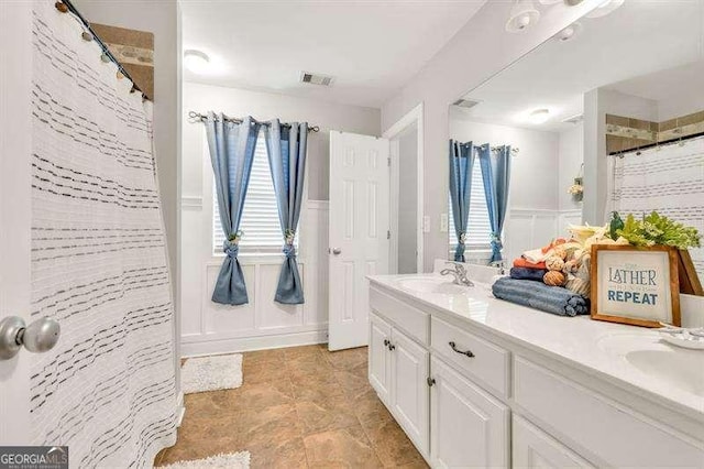 125 Shamus Way, Jefferson, GA 30549 - bathroom featuring double vanity, plenty of natural light, a shower with curtain, wainscoting, and a decorative wall