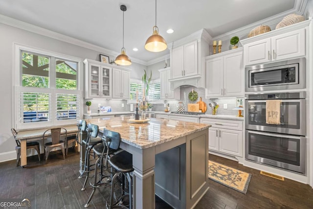 3111 Old Thompson Mill Rd, Buford, GA 30519 - kitchen featuring stainless steel appliances, white cabinets, recessed lighting, a kitchen breakfast bar, and light stone counters