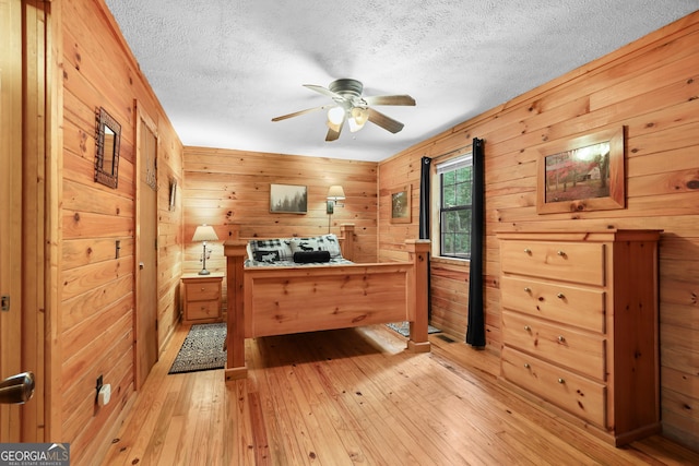 242 Eagles Nest Rd, Sautee Nacoochee, GA 30571 - bedroom with light wood finished floors, a textured ceiling, wooden walls, and a ceiling fan