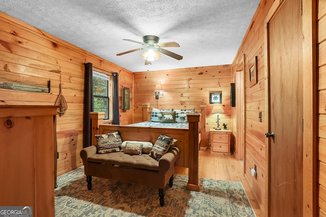 242 Eagles Nest Rd, Sautee Nacoochee, GA 30571 - bedroom with a textured ceiling, wooden walls, light wood-style flooring, and ceiling fan