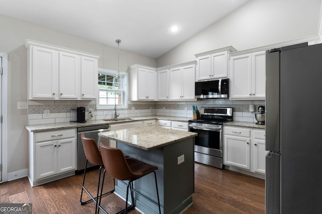 521 Peeples Valley Rd NW, Cartersville, GA 30121 - kitchen featuring appliances with stainless steel finishes, vaulted ceiling, white cabinetry, a center island, and a breakfast bar area