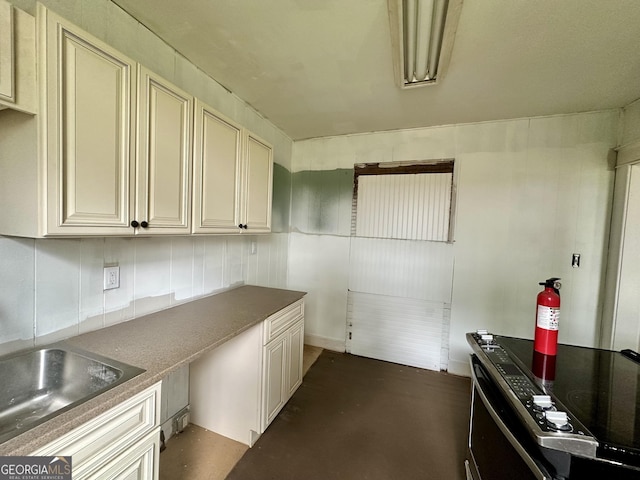 310 Butler St, Waycross, GA 31501 - kitchen featuring range with electric stovetop, cream cabinets, concrete floors, and dark countertops