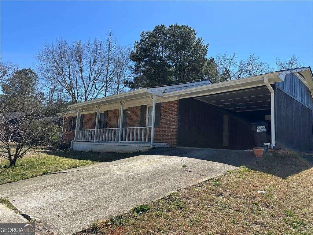 726 Shoreline Trl SE, Conyers, GA 30094 - single story home with driveway, a porch, brick siding, an attached carport, and a front yard