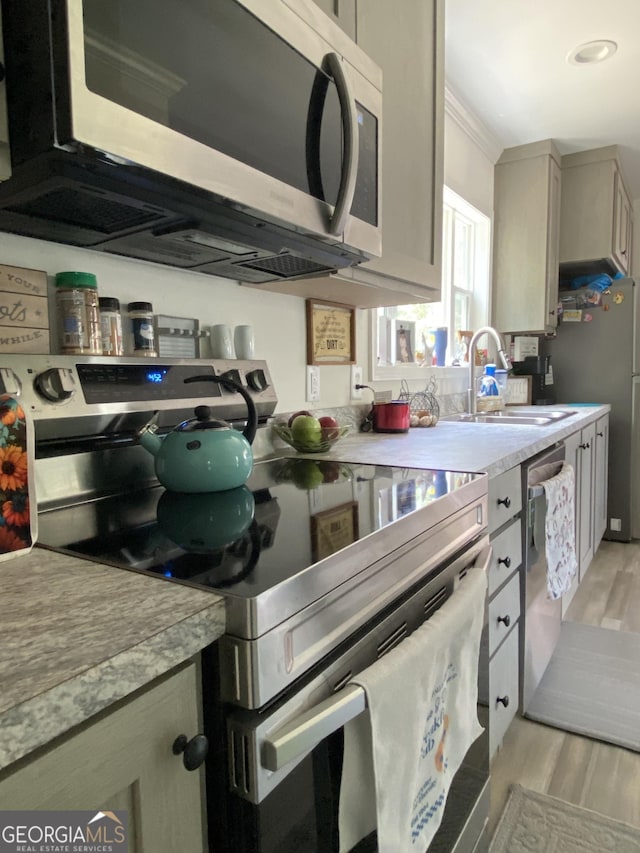 1667 Richard Moore Rd, Dublin, GA 31021 - kitchen featuring stainless steel appliances, a sink, light wood finished floors, light countertops, and ornamental molding