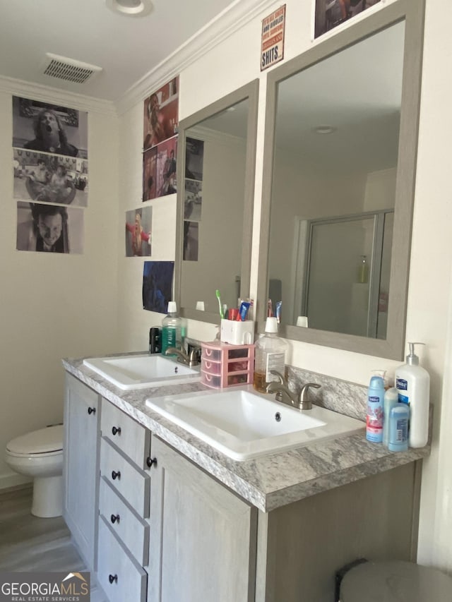 1667 Richard Moore Rd, Dublin, GA 31021 - bathroom with toilet, double vanity, crown molding, a stall shower, and wood finished floors