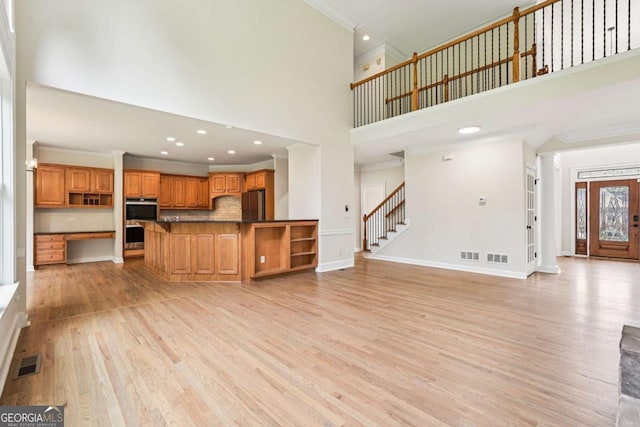 4508 Meadow Vista Trce, Lithonia, GA 30038 - unfurnished living room with a high ceiling, light wood-style flooring, crown molding, stairs, and baseboards