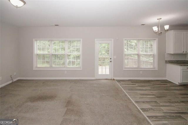 365 Hunt Crk, Acworth, GA 30101 - unfurnished living room with a chandelier, plenty of natural light, baseboards, and dark carpet