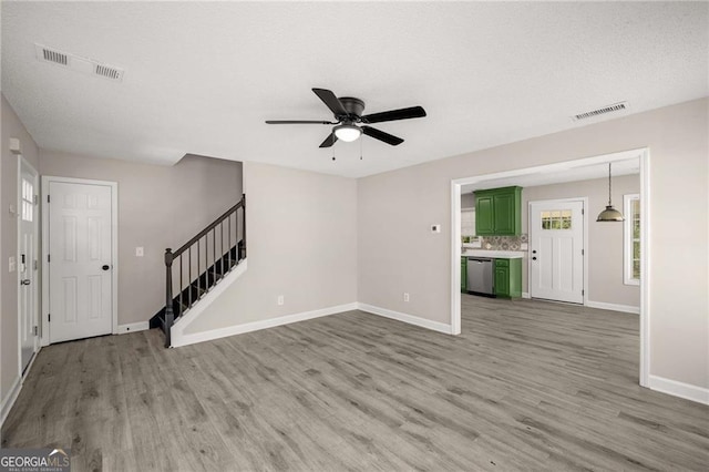 1071 N Price Rd, Sugar Hill, GA 30518 - unfurnished living room featuring wood finished floors, ceiling fan, stairs, and a textured ceiling