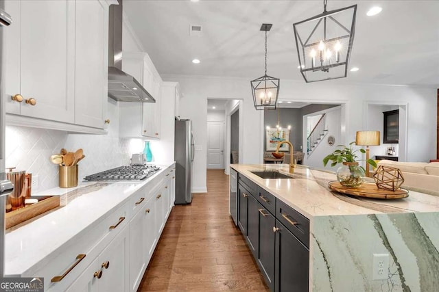 1099 Heyward Way, Alpharetta, GA 30009 - kitchen with wall chimney range hood, a chandelier, appliances with stainless steel finishes, white cabinets, and wood finished floors