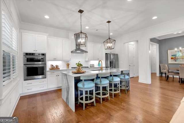 1099 Heyward Way, Alpharetta, GA 30009 - kitchen with appliances with stainless steel finishes, a chandelier, a kitchen island with sink, light countertops, and crown molding