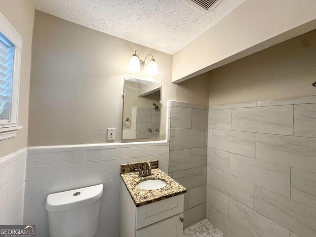 3456 Spring Cir, Decatur, GA 30032 - full bathroom featuring vanity, tile walls, toilet, a textured ceiling, and a tile shower