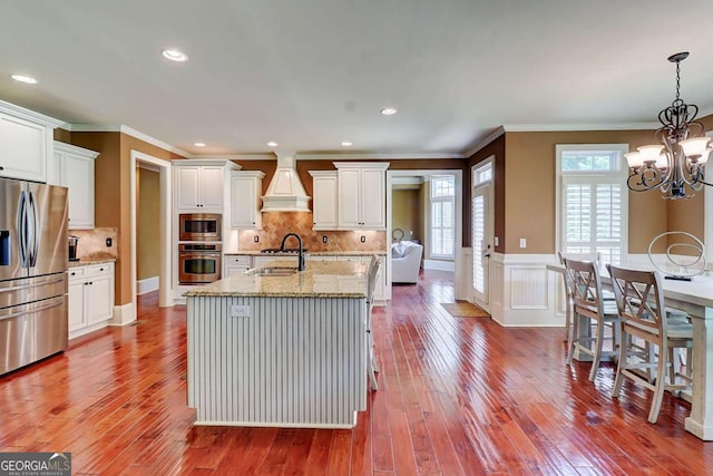 116 Archstone Sq, Mcdonough, GA 30253 - kitchen with appliances with stainless steel finishes, custom exhaust hood, ornamental molding, white cabinetry, and hardwood / wood-style floors