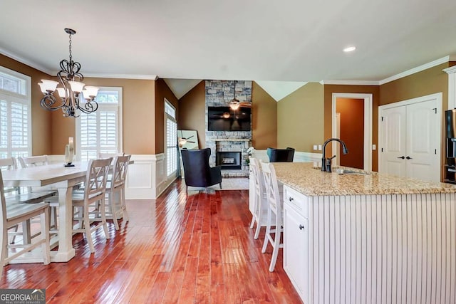 116 Archstone Sq, Mcdonough, GA 30253 - kitchen with wood-type flooring, crown molding, a chandelier, a stone fireplace, and light stone counters