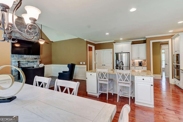 116 Archstone Sq, Mcdonough, GA 30253 - dining area featuring a stone fireplace, crown molding, wood finished floors, wainscoting, and recessed lighting