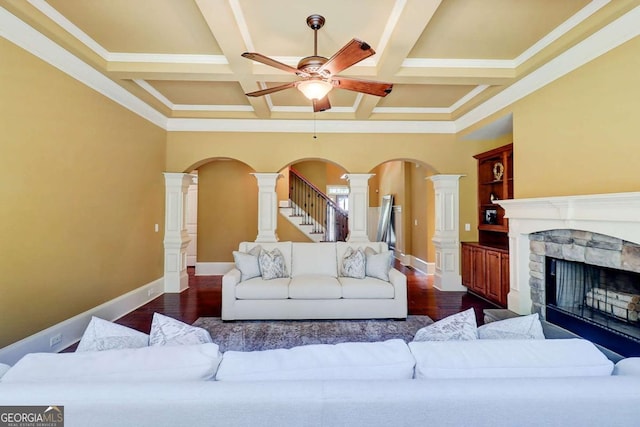 116 Archstone Sq, Mcdonough, GA 30253 - living room with dark wood finished floors, a ceiling fan, a stone fireplace, ornate columns, and coffered ceiling