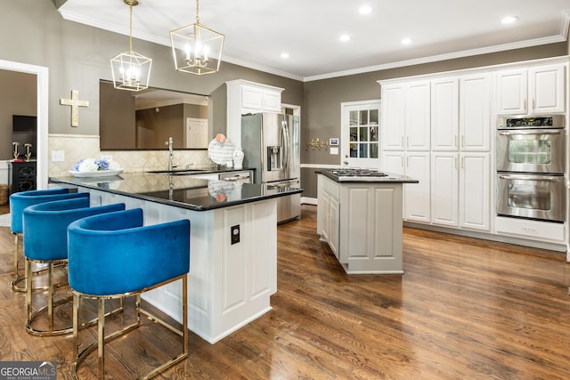 10530 Tuxford Dr, Alpharetta, GA 30022 - kitchen with stainless steel appliances, dark countertops, a center island, white cabinets, and dark wood finished floors