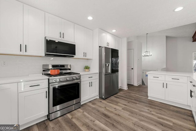 2139 Logan Dr, Jonesboro, GA 30236 - kitchen featuring appliances with stainless steel finishes, light wood finished floors, light countertops, backsplash, and a chandelier