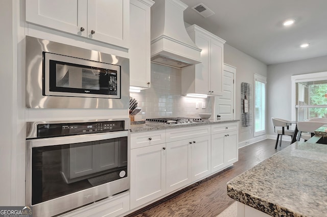 29 Peppertree Dr, Newnan, GA 30265 - kitchen featuring appliances with stainless steel finishes, custom exhaust hood, recessed lighting, white cabinets, and decorative backsplash