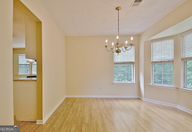 4135 Coursey Lake Rd, Douglasville, GA 30135 - unfurnished room featuring light wood-style floors, a textured ceiling, plenty of natural light, and a chandelier