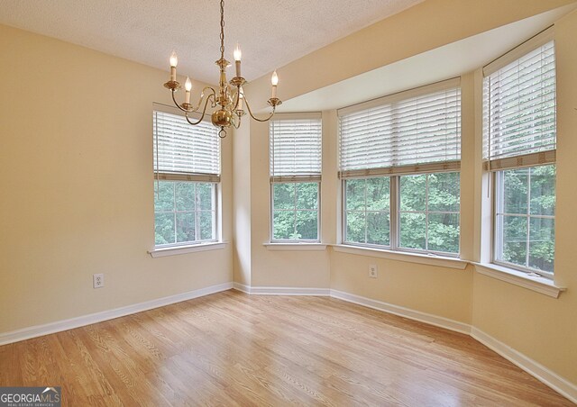 4135 Coursey Lake Rd, Douglasville, GA 30135 - empty room with a chandelier, healthy amount of natural light, light wood finished floors, and a textured ceiling