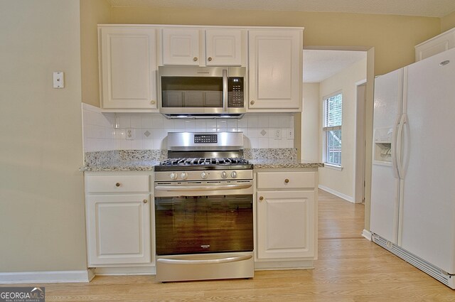 4135 Coursey Lake Rd, Douglasville, GA 30135 - kitchen featuring appliances with stainless steel finishes, light wood-style floors, decorative backsplash, and white cabinetry
