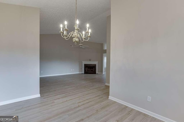 4735 Widgeon Way, Cumming, GA 30028 - unfurnished living room with a chandelier, high vaulted ceiling, wood finished floors, a textured ceiling, and a fireplace