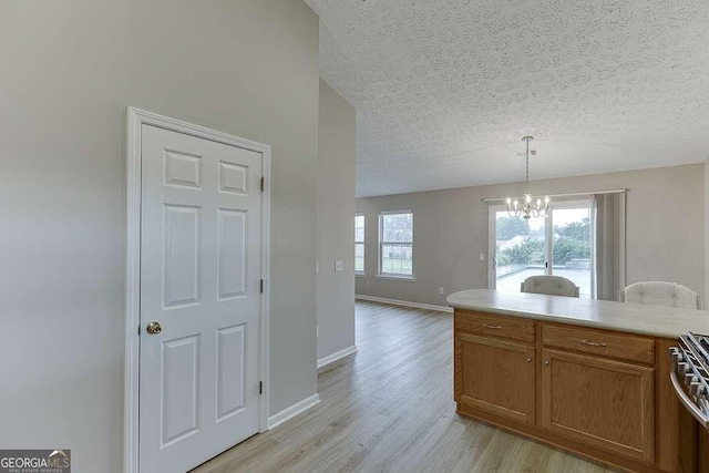 4735 Widgeon Way, Cumming, GA 30028 - kitchen featuring a chandelier, light wood finished floors, a textured ceiling, brown cabinetry, and light countertops