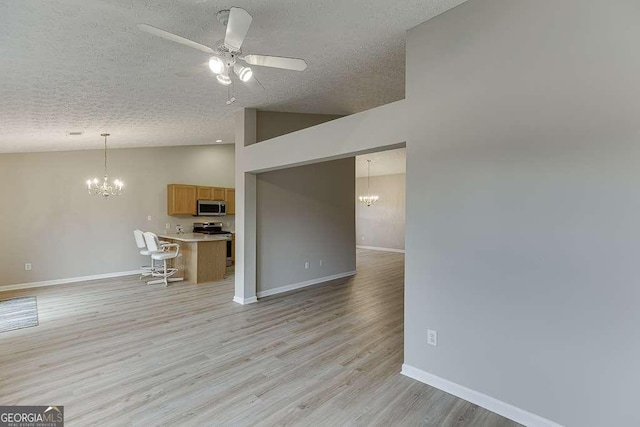 4735 Widgeon Way, Cumming, GA 30028 - unfurnished living room with a chandelier, vaulted ceiling, a textured ceiling, a ceiling fan, and light wood-style flooring