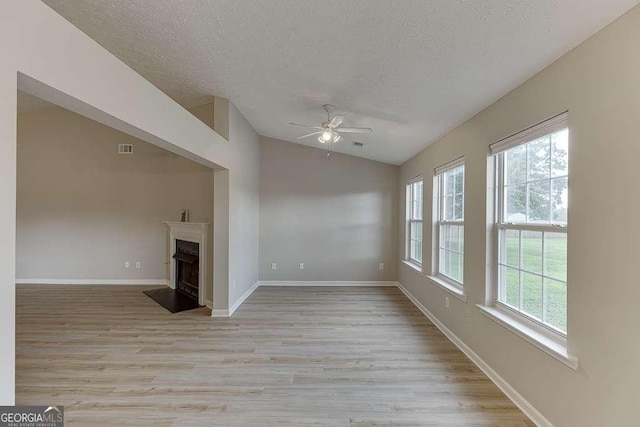 4735 Widgeon Way, Cumming, GA 30028 - unfurnished living room featuring vaulted ceiling, ceiling fan, a textured ceiling, light wood-style flooring, and a fireplace with raised hearth