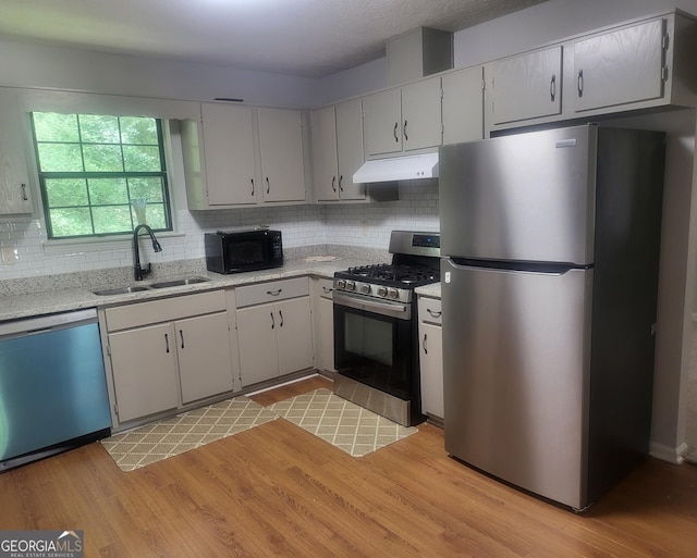 6118 Dana Ct Unit 6, Lithonia, GA 30058 - kitchen with appliances with stainless steel finishes, under cabinet range hood, decorative backsplash, light wood-style floors, and light stone counters