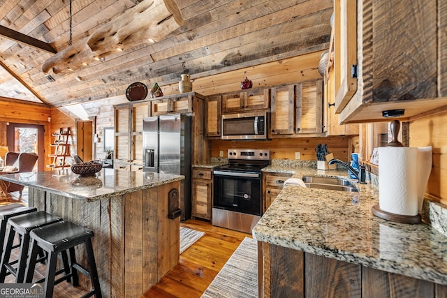307 Big Timber Rd, Mineral Bluff, GA 30559 - kitchen featuring appliances with stainless steel finishes, wooden walls, wooden ceiling, light wood finished floors, and a breakfast bar