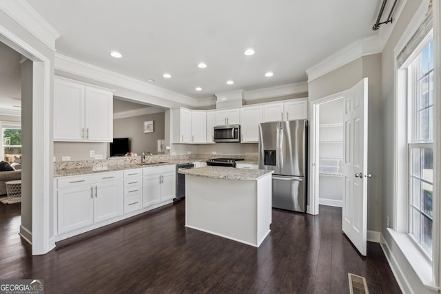 733 Wexford Cove Way, Mableton, GA 30126 - kitchen featuring appliances with stainless steel finishes, a center island, ornamental molding, white cabinetry, and dark wood finished floors