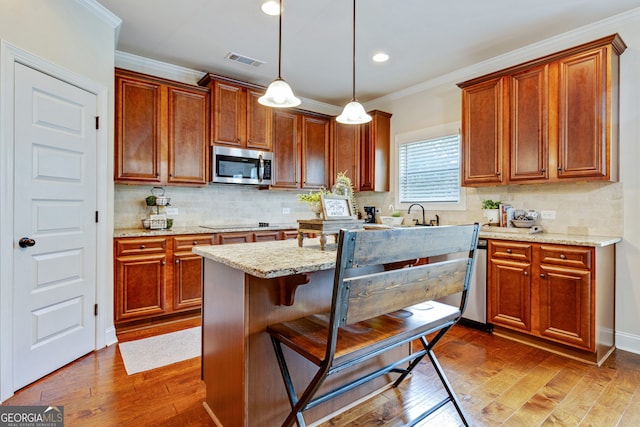 117 Elkins Blvd, Locust Grove, GA 30248 - kitchen with appliances with stainless steel finishes, crown molding, hardwood / wood-style flooring, light stone counters, and a kitchen breakfast bar
