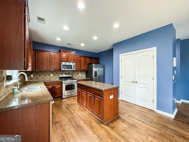 35 Paddle Boat Cv, Senoia, GA 30276 - kitchen featuring stainless steel appliances, light wood finished floors, backsplash, a kitchen island, and dark stone countertops